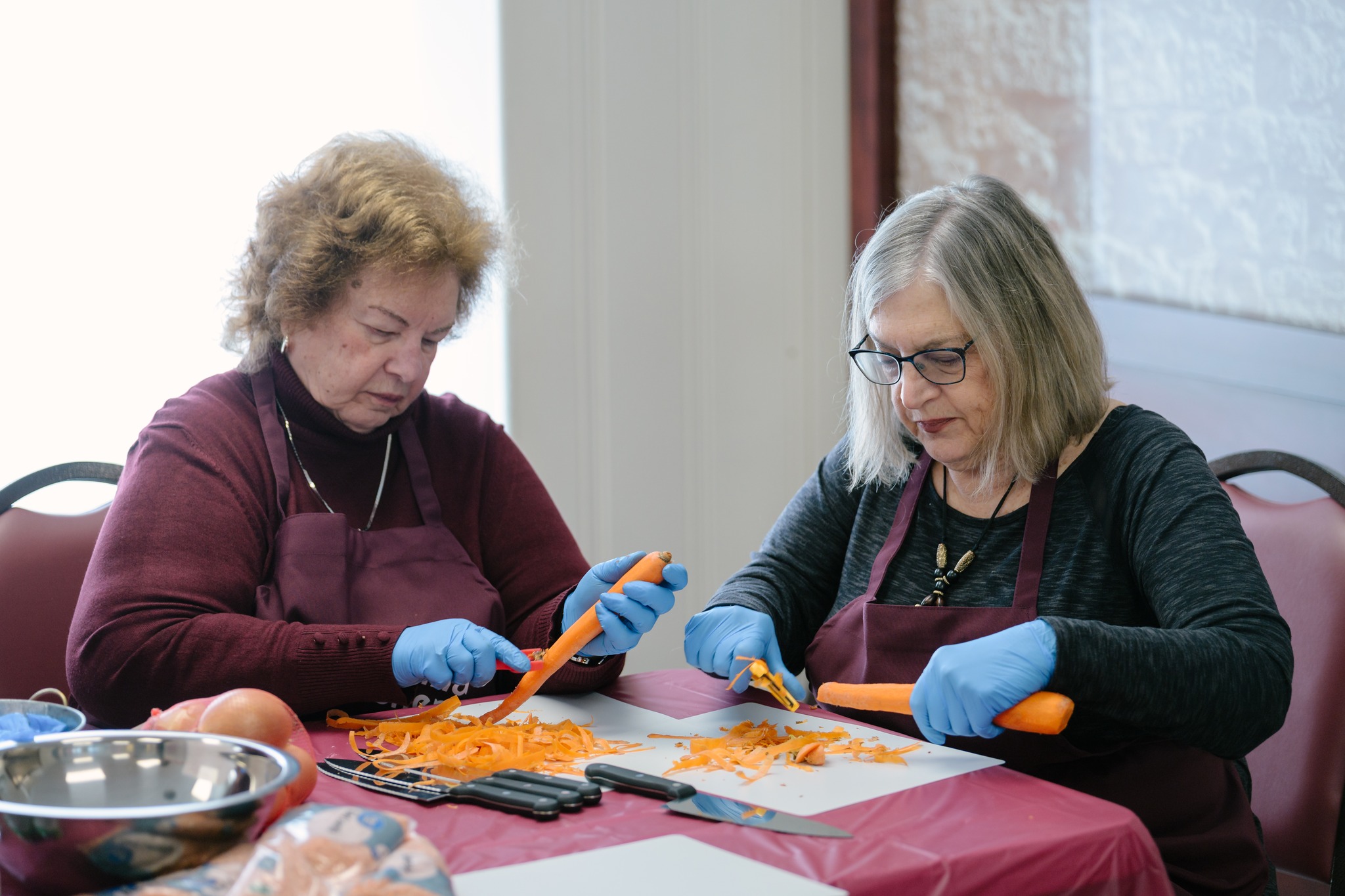 Two volunteers peeling carrots together