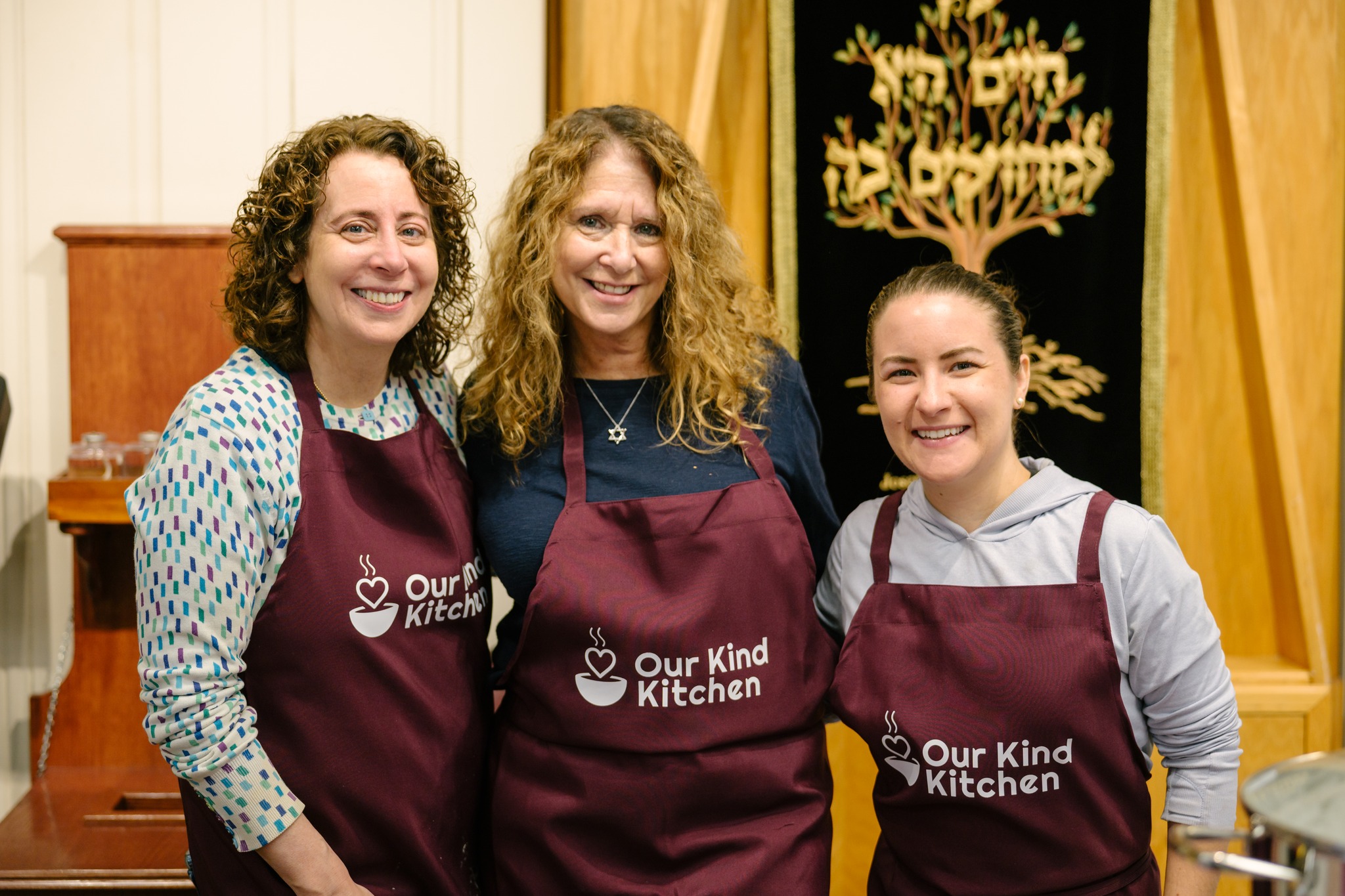 Three volunteers smiling in the kitchen